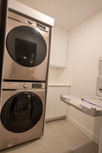 a kitchen with a microwave and a washing machine at Chalet Flodhaus- Bord Rivière St-Maurice (navigable) / SPA /SAUNA - Chalets Galaxia in Saint Roch de Mekinac