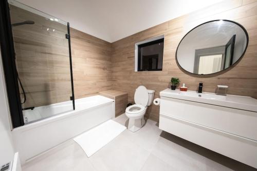 a bathroom with a tub and a toilet and a mirror at Chalet Flodhaus- Bord Rivière St-Maurice (navigable) / SPA /SAUNA - Chalets Galaxia in Saint Roch de Mekinac