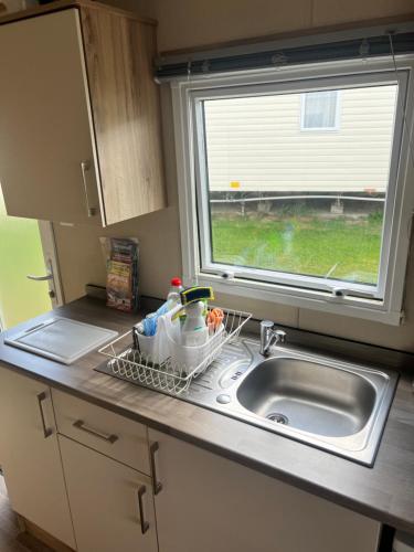 um lavatório de cozinha com um suporte para secar pratos ao lado de uma janela em Oakley Newquay Bay Resorts em Newquay Bay Resort