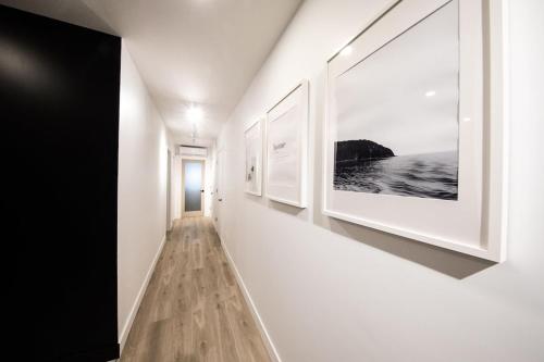 a hallway with white walls and paintings on the walls at Chalet Flodhaus- Bord Rivière St-Maurice (navigable) / SPA /SAUNA - Chalets Galaxia in Saint Roch de Mekinac