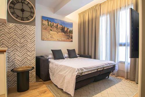1 dormitorio con 1 cama y reloj en la pared en Apartamentos Leonor, en Málaga