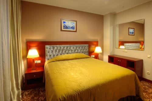 a bedroom with a yellow bed and two lamps at Grand Voyage Hotel in Almaty