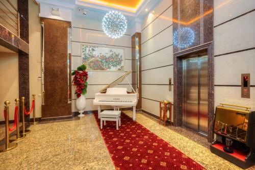 a white piano in a room with a red carpet at Grand Voyage Hotel in Almaty