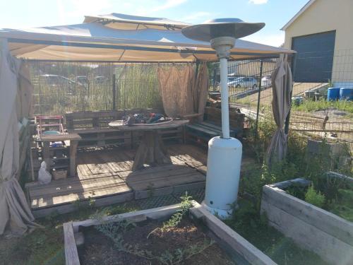 a patio with an umbrella and a table and bench at Cabane Terrasse et potager in Rambouillet