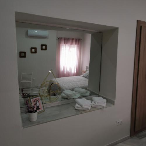 a mirror reflecting a bedroom with a bed and a window at La Peluquería!! in Ronda