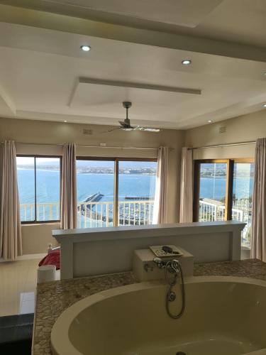 a bathroom with a tub with a view of the ocean at Bikini Beach Manor in Gordonʼs Bay