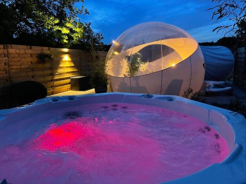a hot tub with a dome in a backyard at night at Bulle du puits avec jacuzzi et sauna privatif in Havinnes