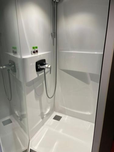 een witte douche met een glazen deur in de badkamer bij Bulle du puits avec jacuzzi et sauna privatif 