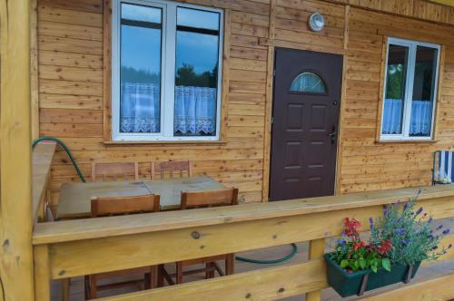 a wooden house with a porch and a door at Domki Snopki in Pisz