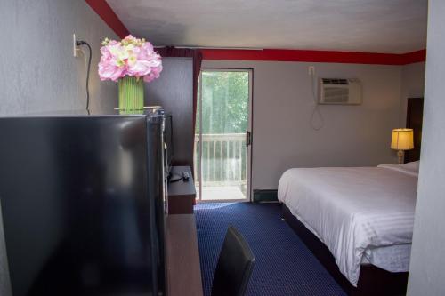 a hotel room with a bed and a vase of flowers at Travel inn in North Kingstown