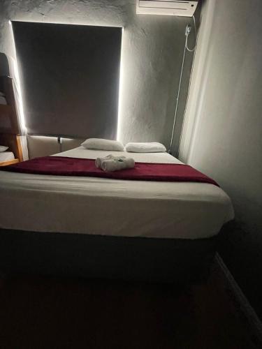 a small bed in a small room with a light at Esquina 8 Suítes Confort & Hostel in Florianópolis