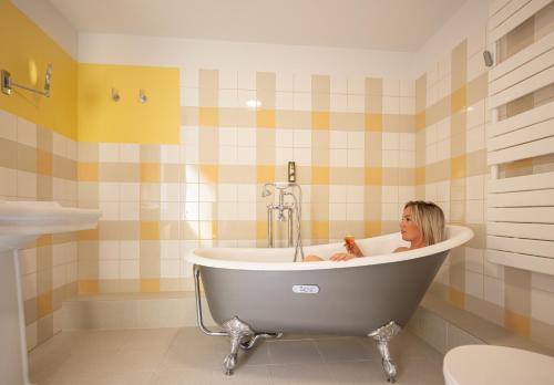 a woman sitting in a bath tub in a bathroom at Hôtel-Restaurant du Mouton in Ribeauvillé