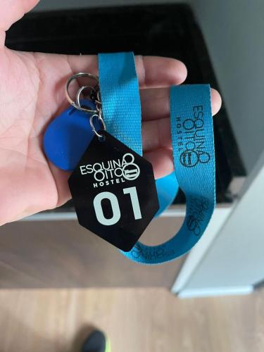 a hand holding a keychain with a key chain with at Esquina 8 Suítes Confort & Hostel in Florianópolis