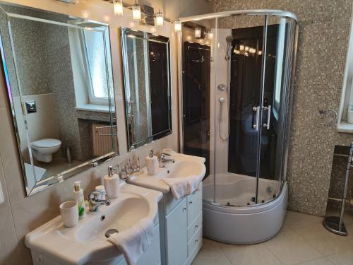 een badkamer met 2 wastafels, een douche en een bad bij Vila Prag in Praag