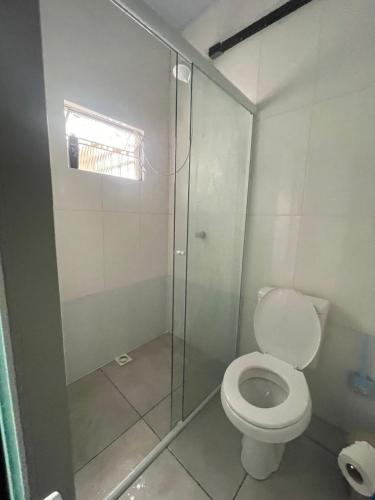 a bathroom with a toilet and a glass shower at Esquina 8 Suítes Confort & Hostel in Florianópolis