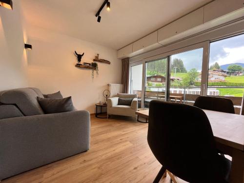 sala de estar con mesa, sillas y ventana grande en Alpen Studio Ellmau I, en Ellmau