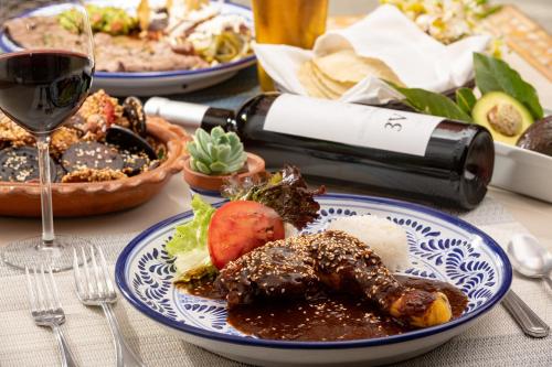 a table with plates of food and a glass of wine at Hotel Boutique Casona de la China Poblana - Adults Only in Puebla