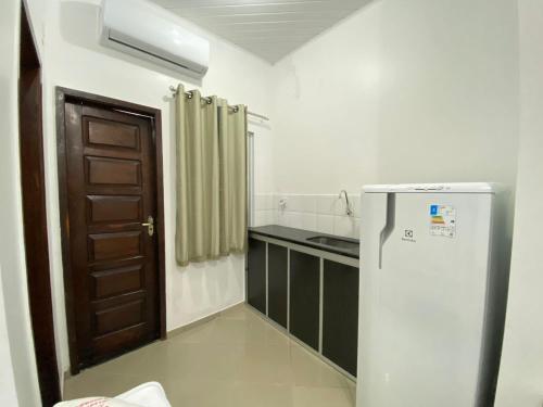 Il comprend une petite cuisine avec un réfrigérateur et une porte. dans l'établissement Hotel SALINE PRAIA, à Salinópolis