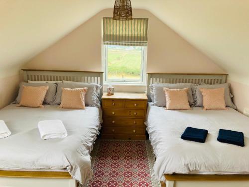 two twin beds in a attic room with a window at The Loft - Shemara 