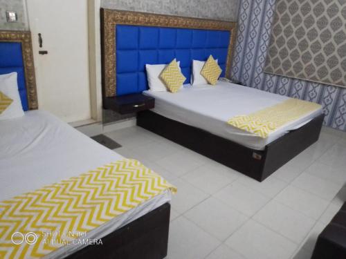 two beds in a room with blue and yellow pillows at E- Town Guest House karachi in Karachi