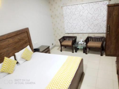 a bedroom with a bed and two chairs and a table at E- Town Guest House karachi in Karachi