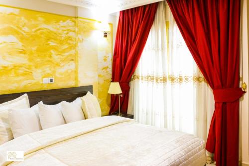 a bedroom with a bed with red curtains and a window at Noubou International Hotel in Douala