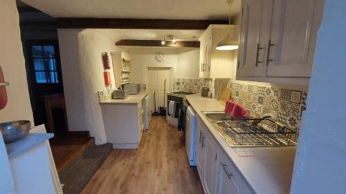 una cocina con encimeras blancas y armarios blancos en Wellington Farm Devon near Heritage Coast beaches & AOBN- dog friendly en Honiton