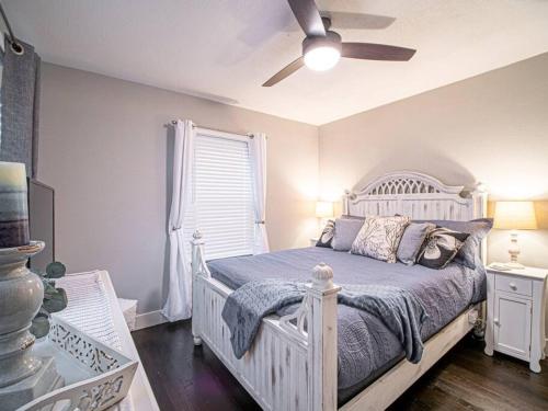 1 dormitorio con 1 cama blanca y ventilador de techo en Homey Bungalow Convenient to Marietta and I-75!, en Marietta