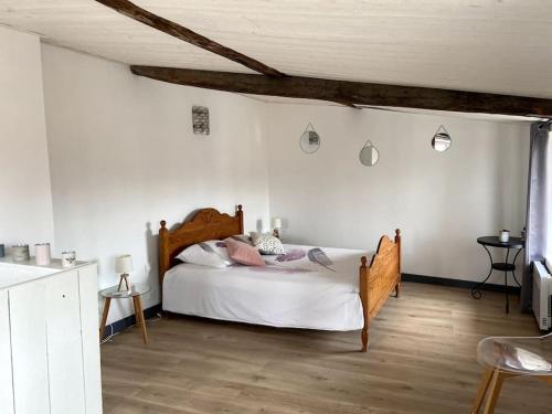 Schlafzimmer mit einem Bett mit weißen Wänden und Holzböden in der Unterkunft la maison du dauphin in Marans