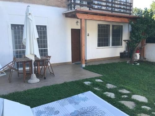 um pátio com um guarda-sol, uma mesa e cadeiras em Casaflavio em Torvaianica