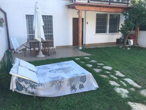 a patio with a table and an umbrella on the grass at Casaflavio in Torvaianica