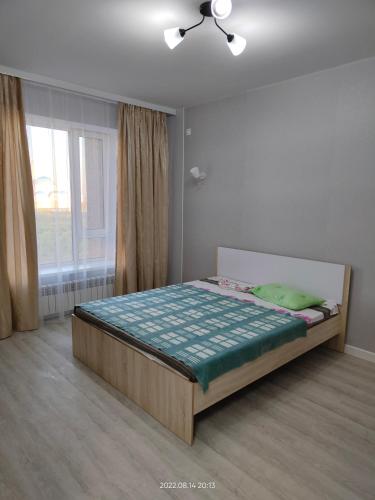 1 dormitorio con 1 cama en una habitación con ventana en Жк Будапешт en Prigorodnyy