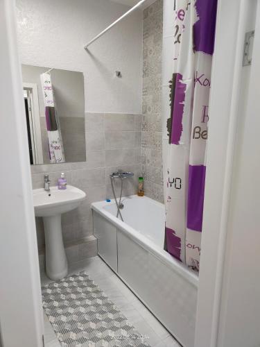 y baño con lavabo, bañera, aseo y cortina de ducha. en Жк Будапешт en Prigorodnyy