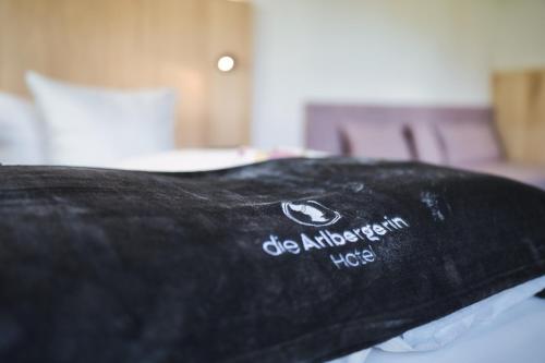 a black pillow sitting on top of a bed at Hotel Die Arlbergerin - Design & Tiroler Gemütlichkeit in Sankt Anton am Arlberg
