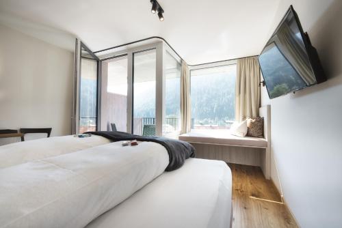 two beds in a room with a large window at Hotel die Arlbergerin ADULTS FRIENDLY 4 STAR in Sankt Anton am Arlberg