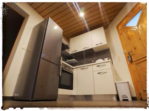 una cocina con nevera de acero inoxidable y armarios blancos en Casa Mirada, en Trin