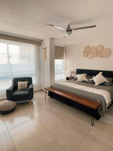 a bedroom with a large bed and a chair at Hermoso Departamento Nuevo a 50 metros de playa!! in Manzanillo