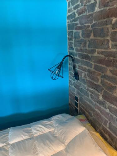 a bed in a room next to a brick wall at Unique space in Gerakas - Cave in Athens