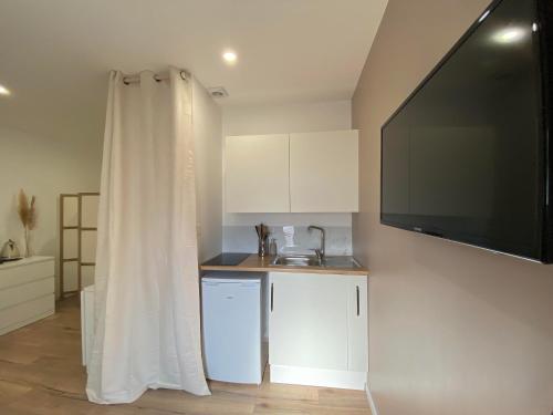 a kitchen with white cabinets and a flat screen tv at maison moderne proche centre ville/hôpital in Angers