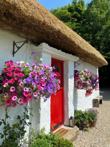 a small house with a red door and flowers at Keenaghan Cottage Belleek Fermanagh Northern Ireland in Belleek
