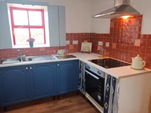 a kitchen with blue cabinets and a sink at The Old Mill, Kilcorkey, Bellanagare, Castlerea, County Roscommon - West of Ireland in Bellanagare