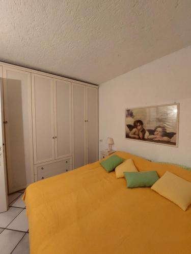 a bedroom with a bed with orange sheets and green pillows at Appartamento a Punta Asfodeli in Porto Rotondo