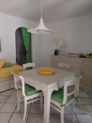 tavolo bianco da pranzo con due sedie e un piatto di Appartamento a Punta Asfodeli a Porto Rotondo