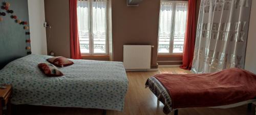 a bedroom with a bed and two windows at Maison de village au coeur des Combrailles in Montaigut-en-Combraille