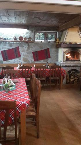 a dining room with tables and chairs and a fireplace at Guest House Todorini kashti in Koprivshtitsa