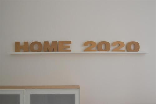 una señal de casa en la parte superior de una pared blanca en HOME 2020: COME A CASA! FEEL AT HOME! WIE ZUHAUSE!, en Giussano