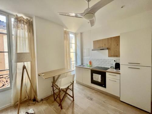 une cuisine avec des placards blancs et une table. dans l'établissement Bohème Chic - parking- 80m des arènes, à Nîmes