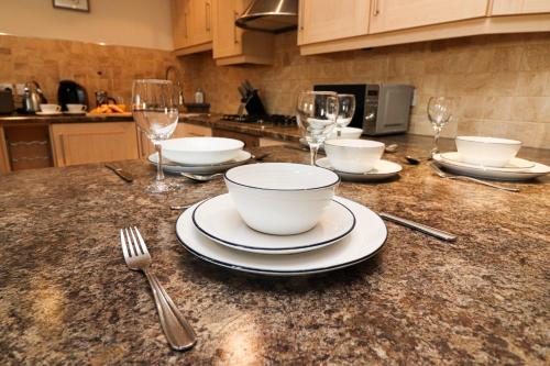 a kitchen counter with plates and bowls and wine glasses at A superb large 1 bedroom apartment in Ramsbottom in Ramsbottom