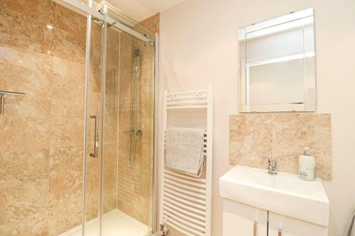 A superb large 1 bedroom apartment in Ramsbottom في رامزبوتوم: حمام مع دش ومغسلة ومرآة