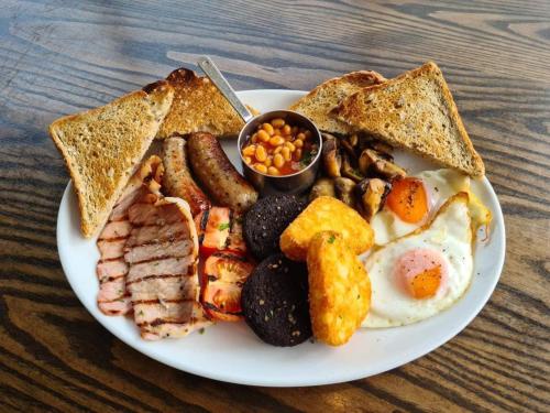- une assiette de petit-déjeuner avec des œufs, du bacon grillé et des haricots dans l'établissement The Woolpack Inn, à Kettering